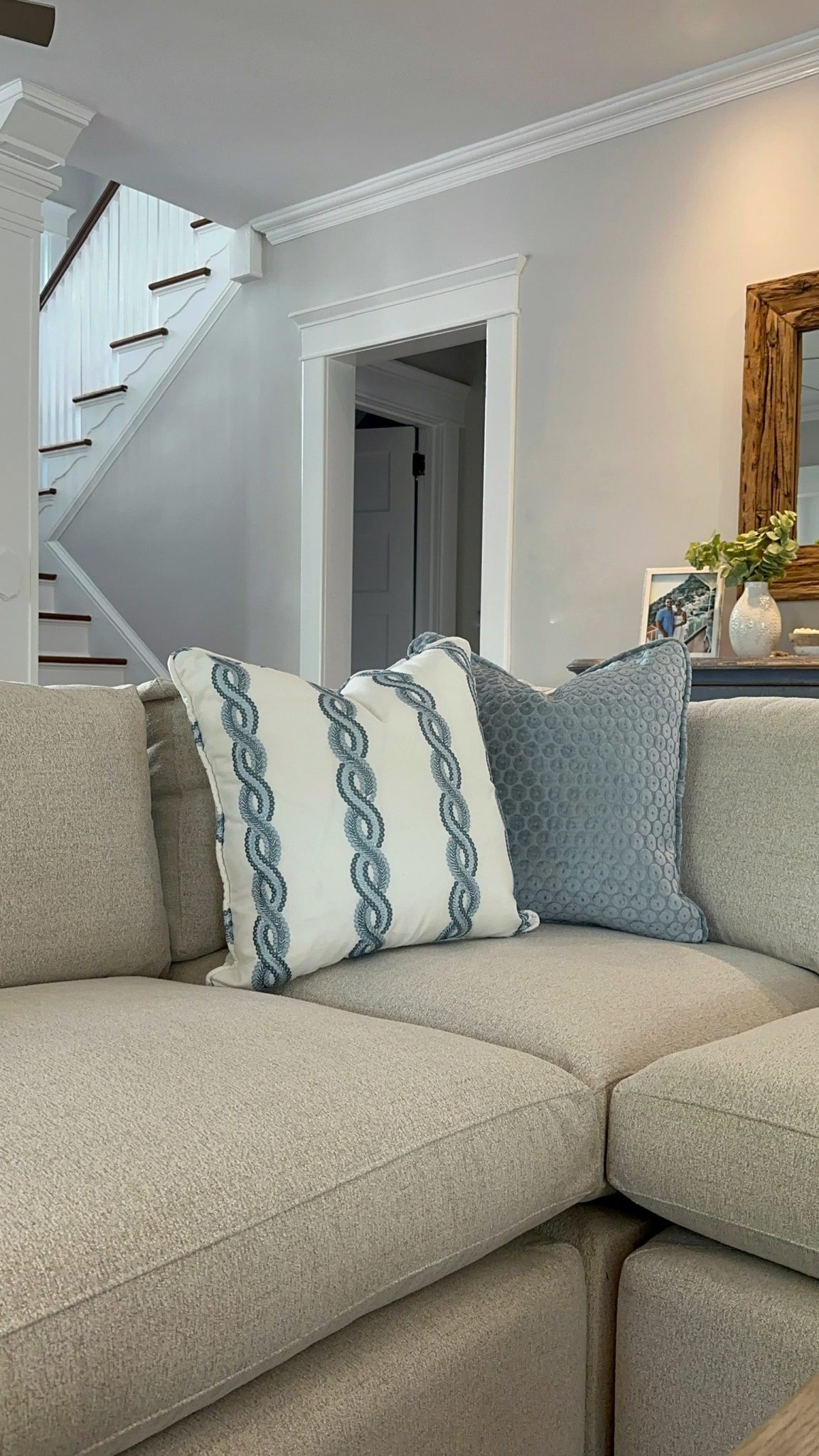 A sectional couch in a stylish living room with stairs, featuring a sophisticated interior design.