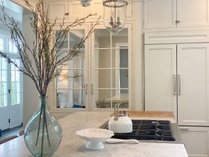 A kitchen with white cabinets and a vase of flowers showcasing an immaculate interior design.