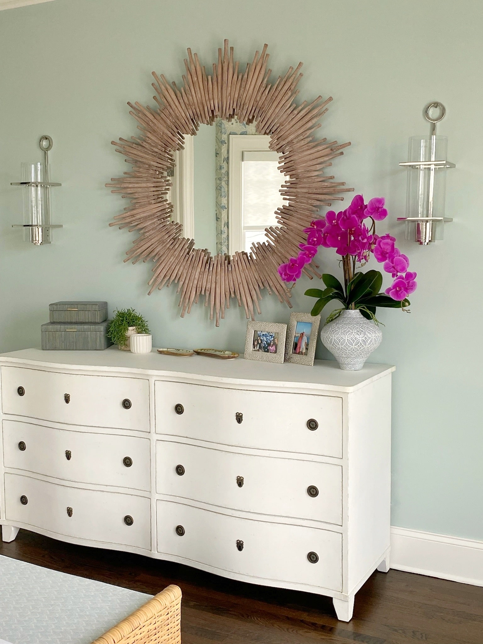 A white dresser adorned with a beautiful sunburst mirror, perfect for adding an elegant touch to any interior design.
