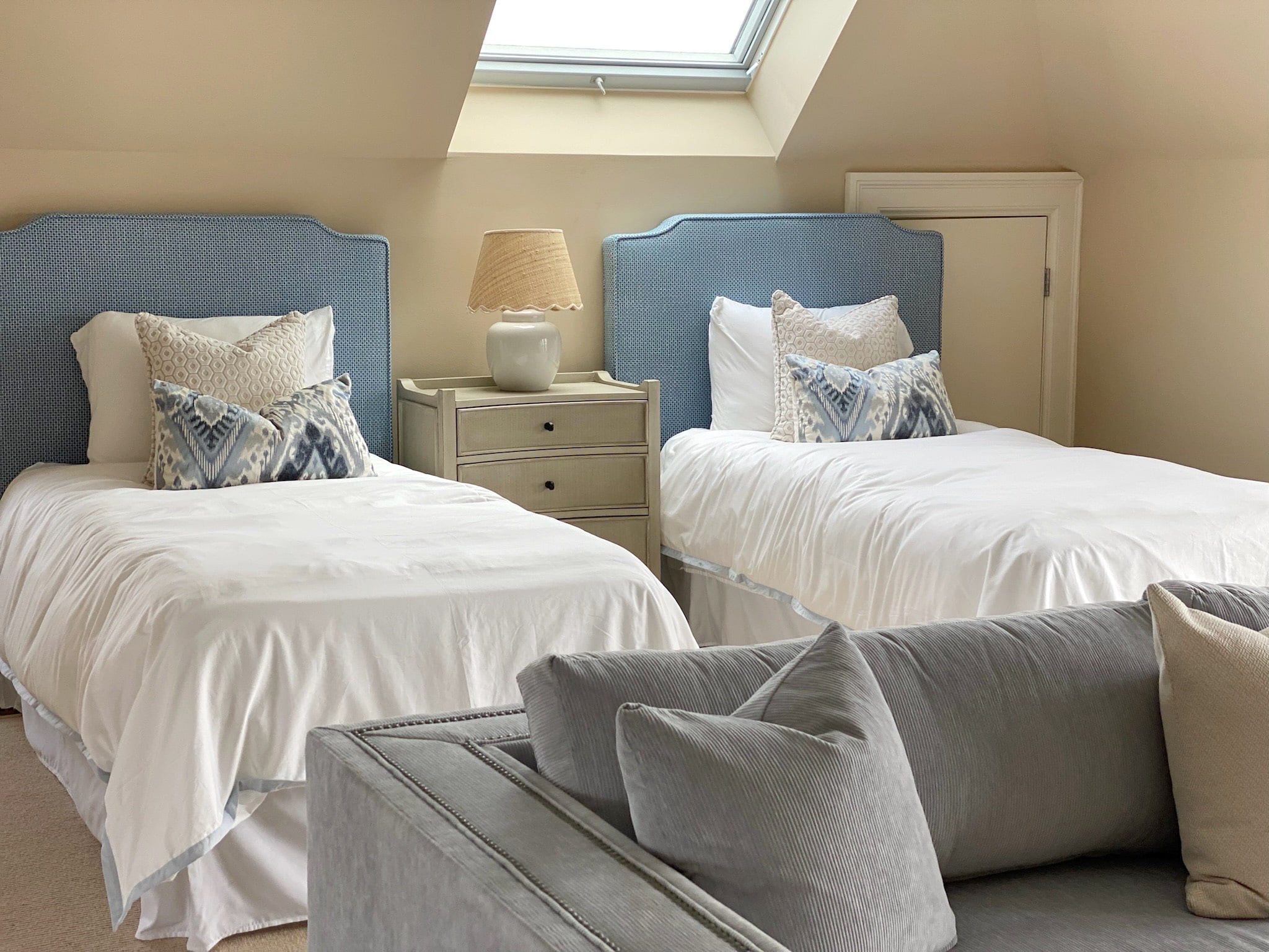 A room with two twin beds showcasing a skylight feature, designed with an exquisite touch of interior design.