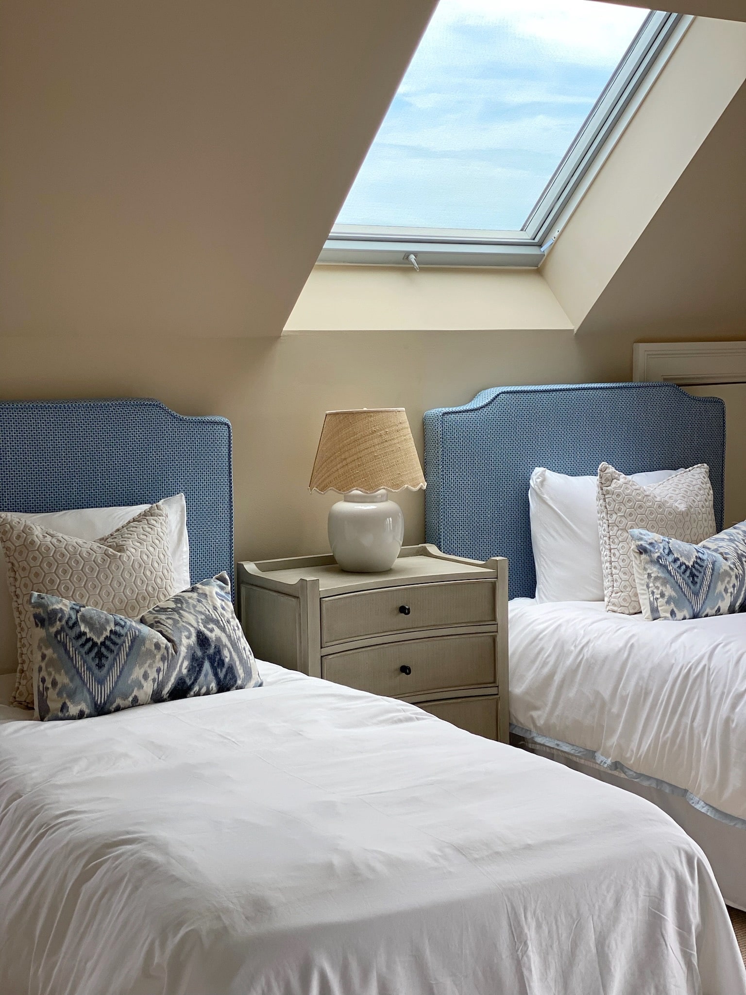 A stylishly designed bedroom with two beds and a skylight.