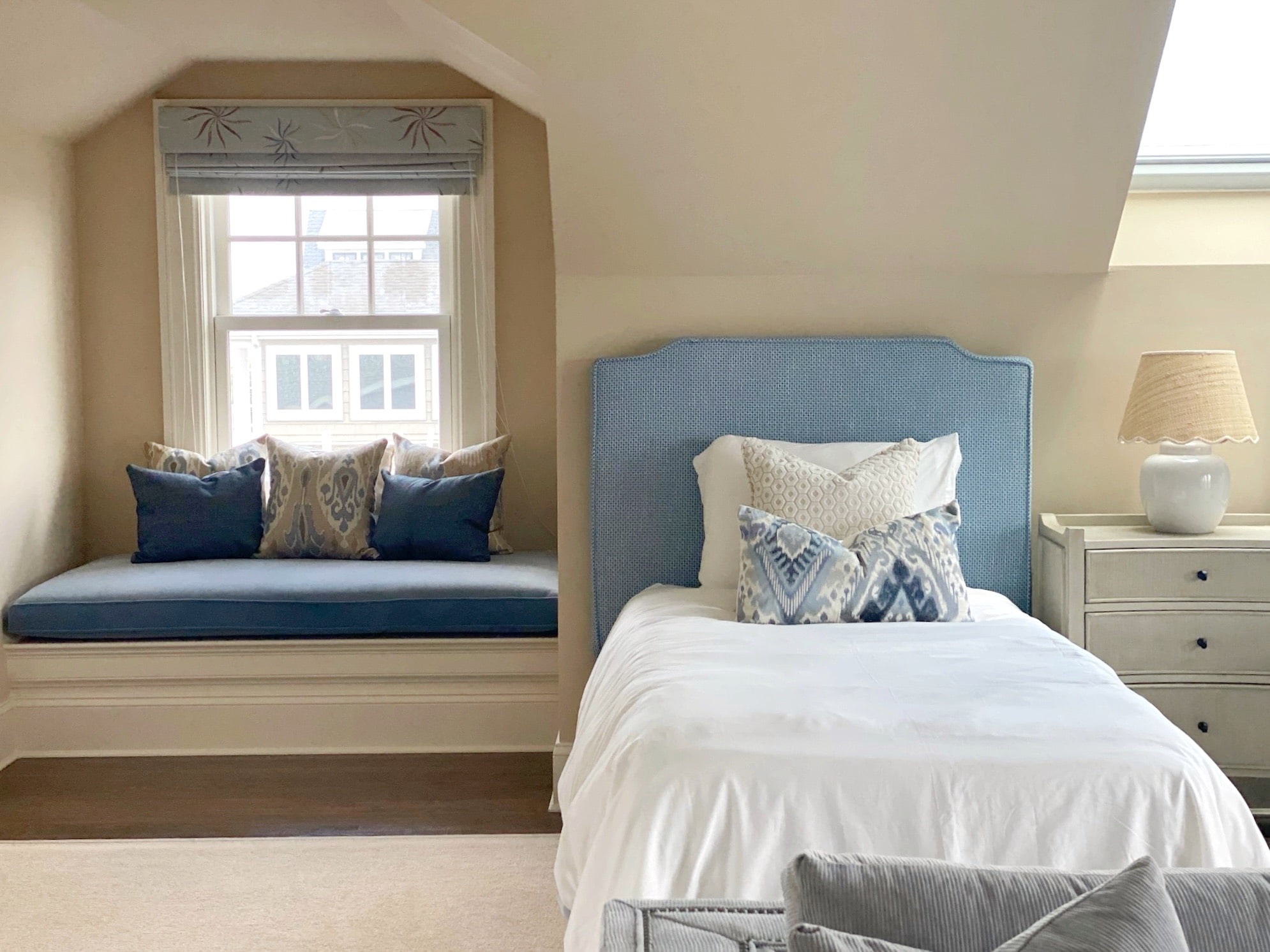 A blue and white bedroom with a window seat showcasing interior design.