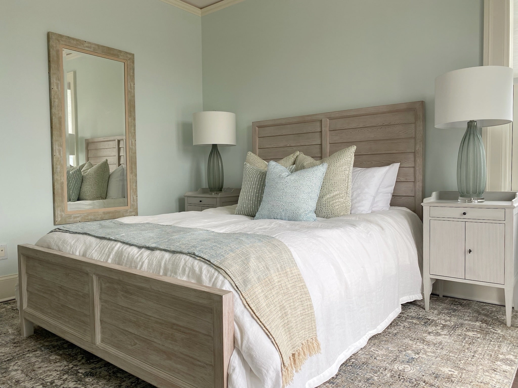 A bedroom with light blue walls and a white bed, designed with an appealing interior design.