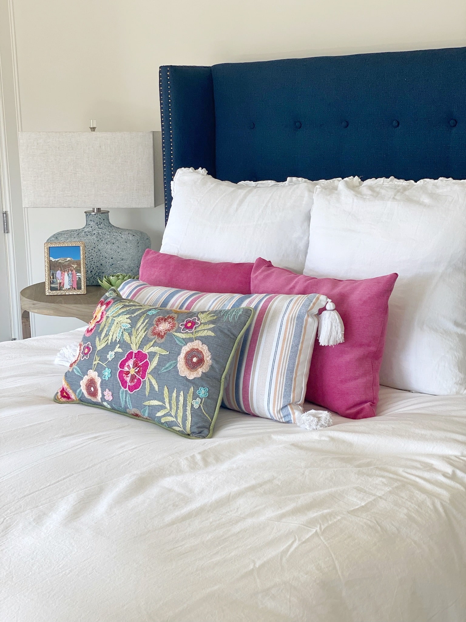 A bed with a blue upholstered headboard and pillows, designed to enhance the interior design of any room.